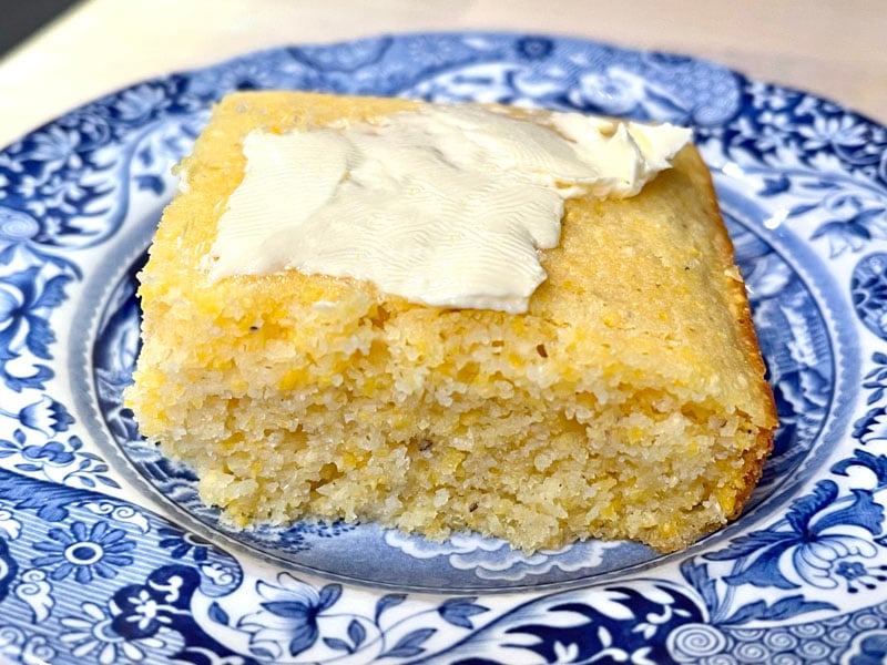 Slice of Gluten Free Cornbread on a saucer, topped with butter